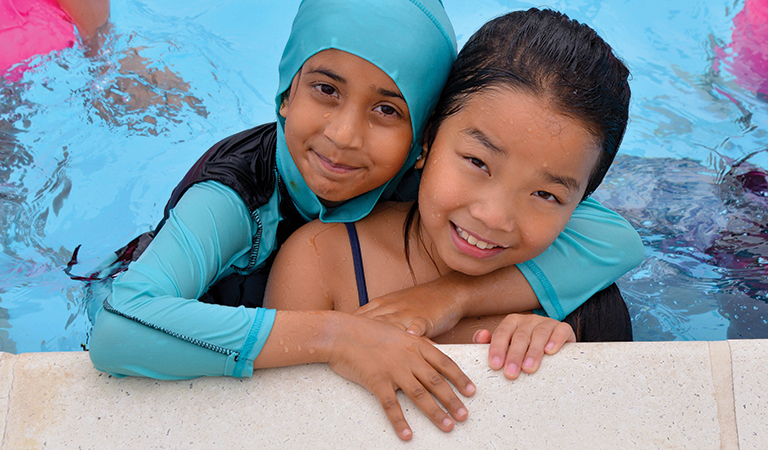 two children smiling in a swiming pool